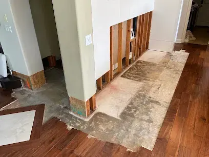 A hallway with the flooring cut back and the lower walls opened for drying