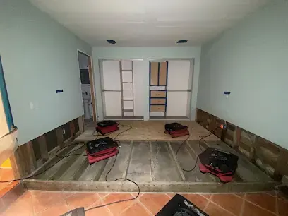 Air movers set across an opened subfloor in an emptied room