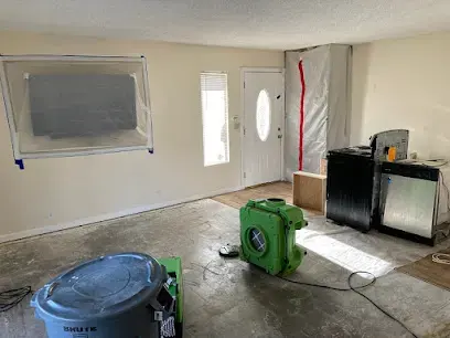 A green air mover, plastic sheeting and a bin set up in a front room during drying in Imperial Beach